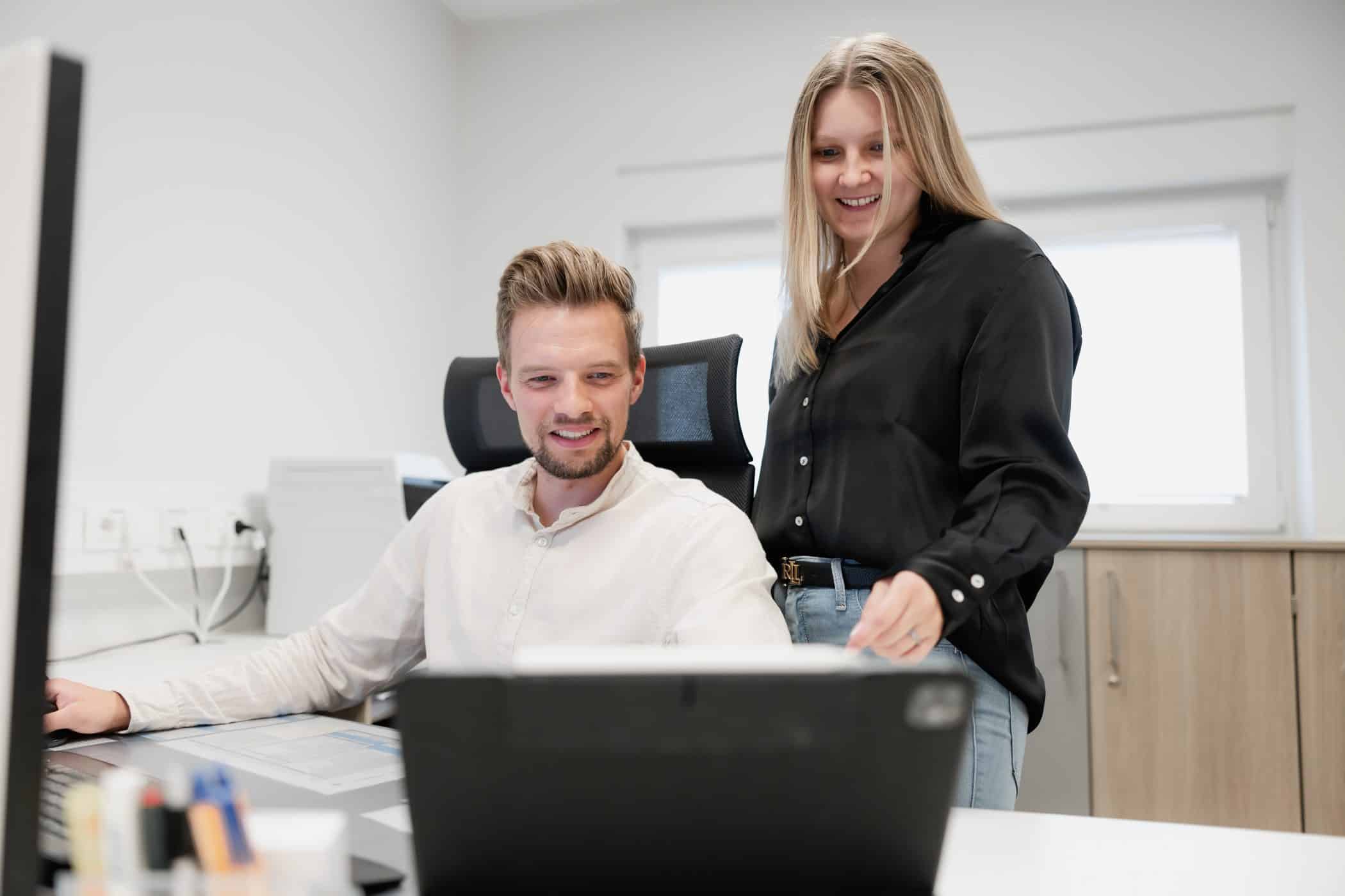 Zwei Mitarbeitende arbeiten gemeinsam am Laptop im Buero bei IVT in Oberhausen