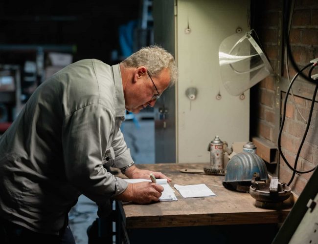 Mitarbeiter schreibt Notizen auf Werkbank