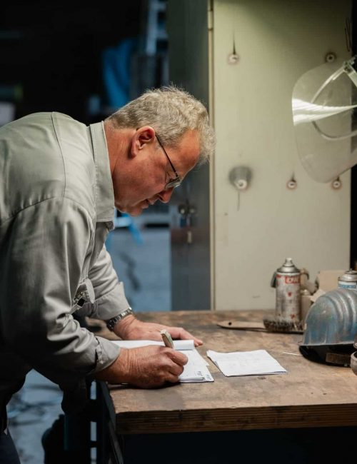 Mitarbeiter schreibt Notizen an Werkbank in Werkstatt