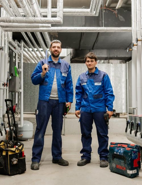 Zwei Monteure stehen in technischer Anlage mit Werkzeug