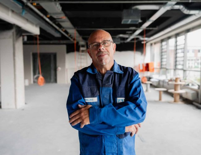 Mitarbeiter in Arbeitskleidung steht in Produktionshalle