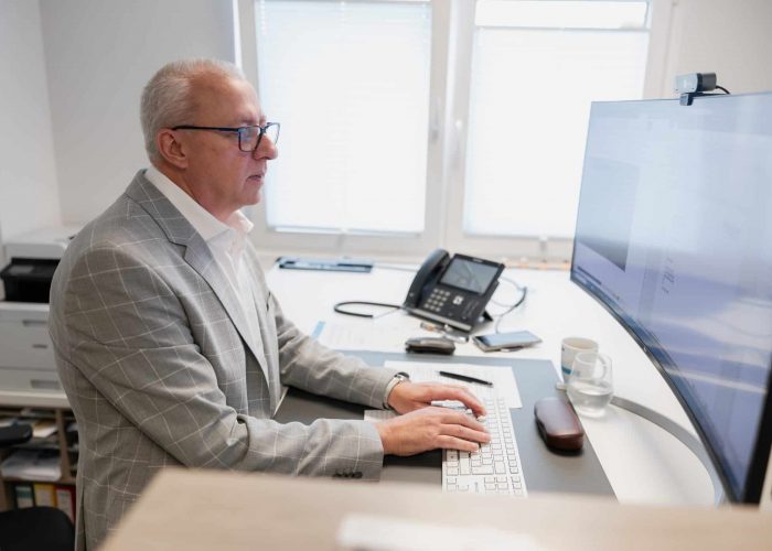 Aelterer Mann im Anzug arbeitet am Computer im Buero