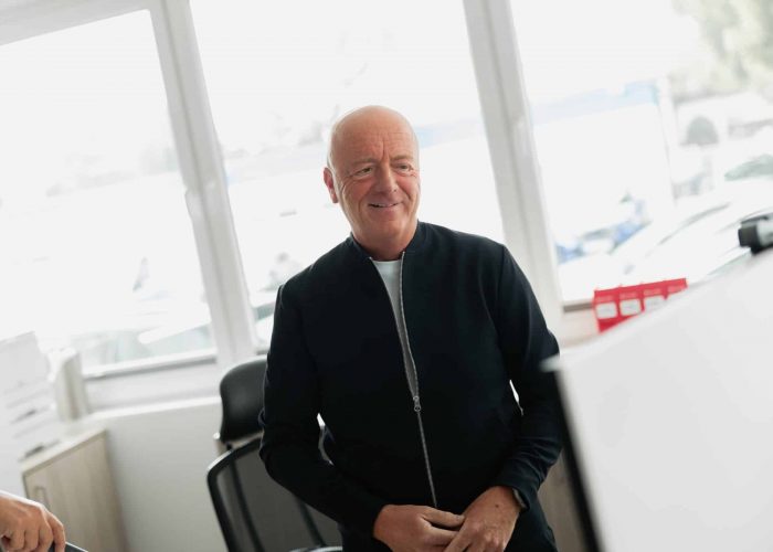 Mitarbeiter steht laechelnd im Buero